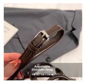 Detail showing the adjustable brown faux leather shoulder strap with silver metal buckle