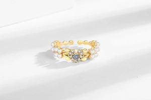 Détail de la bague nœud dorée avec zircon en cœur et finitions en perles