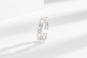 Gros plan de la bague nœud argentée ajustable avec perles sur fond minimaliste blanc