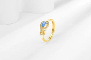 Detail of a gold pear-cut blue zircon ring featuring a micro-paved diamond halo and open band