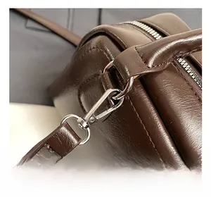 Detail shot of sturdy silver metal hook and strap connection on a brown leather bag