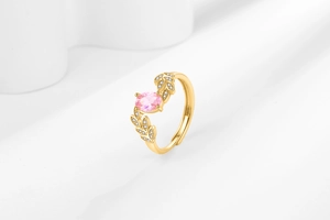 Detailed macro view of gold leaf ring featuring pink oval stone and zircon accents