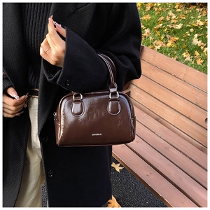 Deep brown glossy patent leather Boston bag with white logo and retro top handle details