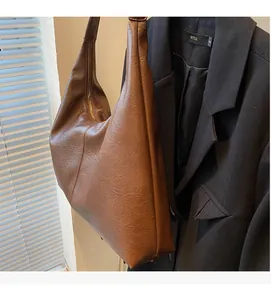 Close-up of brown textured leather tote bag with gold zipper next to a black blazer