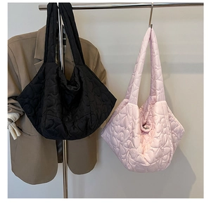 Detail of heart quilted large puffer tote bag in black and pink with soft down-like texture