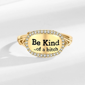 Gold oval ring with Be Kind slogan and zircon border on a clean white background