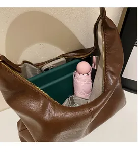 Top view of spacious brown leather tote bag filled with tablet, umbrella and perfume