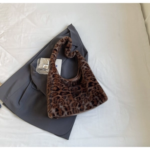 Close-up of leopard print faux fur tote bag with brown leather lining on gray fabric