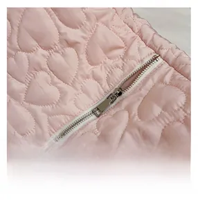 Detail of pink quilted tote bag showing heart-shaped stitching and silver metal zipper