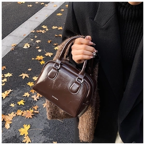 Detail of dark brown glossy bowling bag with silver rings on a fall leaf street
