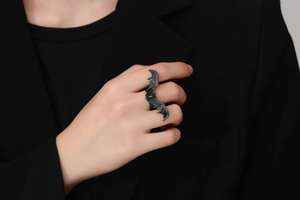 Close-up of black gothic bat ring with detailed wings worn on index finger in dark style