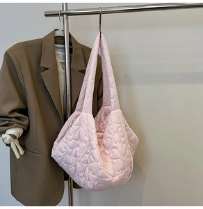 Detail of pink quilted tote bag with heart embroidery hanging on a metal hanger