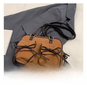Détail du sac bandoulière vintage marron avec poches symétriques et nœud décoratif