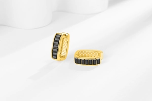Detail of gold U-shaped earrings with black zircon stones and hollow diamond pattern