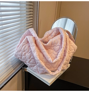 Detail of light pink tote bag with heart-shaped quilted pattern and soft padded fabric texture