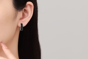 Close-up of U-shaped silver earrings with black rectangular stones on model's ear