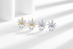 Close-up of crown-shaped pearl earrings with marquise-cut zircons in gold and silver