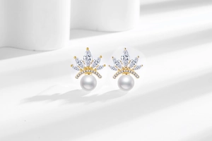 Macro detail of elegant crown pearl earrings with marquise stones and gold plating