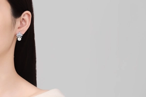 Detailed view of elegant crown-shaped pearl earrings with cubic zirconia on model