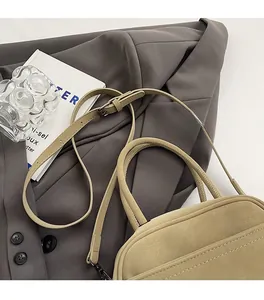 Close-up of adjustable shoulder strap and leather handle on a beige Boston square bag