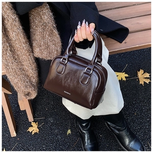 Detail of a dark brown glossy bowling bag with QIAOSHE logo and silver hardware