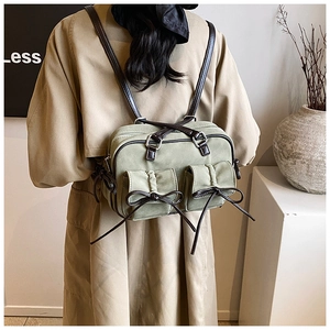 Detail of sage green vintage backpack featuring brown leather accents and bow details
