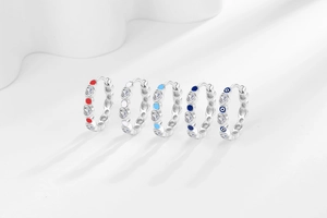 Close-up of five heart-shaped evil eye hoop earrings in various vibrant colors