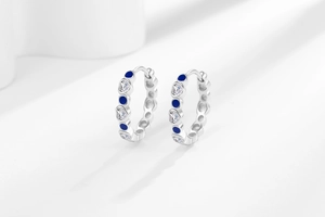 Detailed close-up of heart-shaped zircon and blue crystal huggie hoop earrings