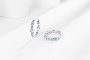 Macro detail of silver heart earrings with blue accents and sparkling clear crystals