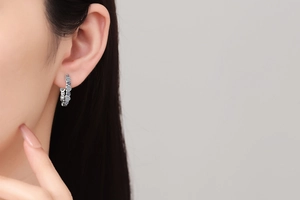 Close-up of evil eye heart hoop earrings with blue and white crystals on silver metal