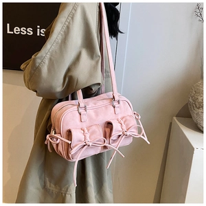 Detail of pink suede shoulder bag featuring drawstring bow pockets and pleated texture