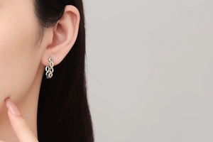 Detail of twisted two-tone hoop earring with shimmering zircons on a female model