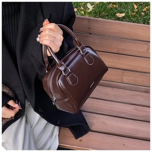 Close-up of a dark brown glossy patent leather bowling bag with silver zipper detail