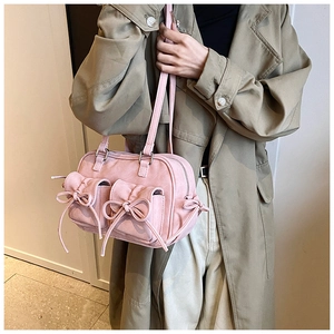 Detail of pink faux suede shoulder bag with dual bow drawstring and soft texture