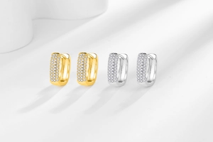 Close-up of gold and silver U-shaped huggie hoop earrings with micro-paved cubic zirconia