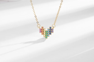Macro shot of gold heart pendant with rainbow zircon stones on fine chain necklace