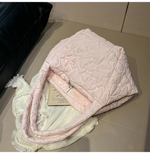 Detailed view of pink heart-quilted puffer bag with silver zipper and soft handle