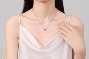 Close-up of rainbow heart pendant necklace worn on neck with elegant silk attire