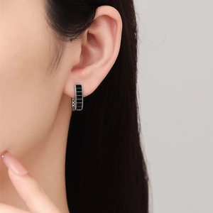 U-shaped silver huggie earrings with black rectangular inlay and hollow side patterns