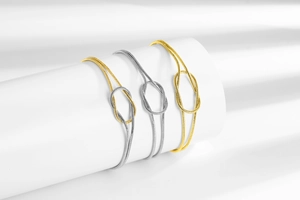 Detail of minimalist knotted snake chain bracelets in gold, silver, and two-tone finishes