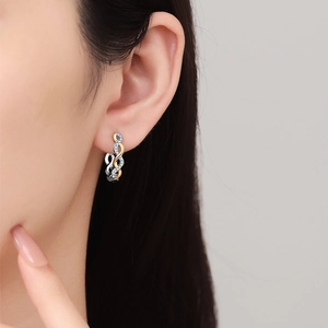 Twisted two-tone gold and silver earrings with pavé zircons worn on model ear