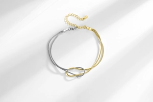Detail of silver and gold snake chain bracelet with central knot and lobster clasp