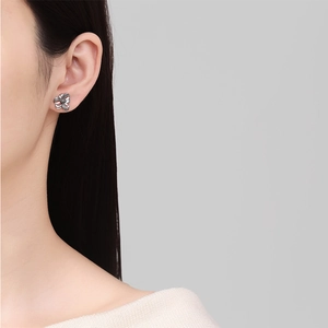 Orecchini a perno a fiore traforato minimalisti in argento indossati da modella