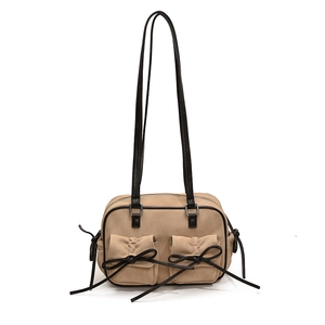 Detail of khaki shoulder bag with dual front pockets and black leather bow accents