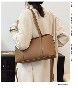 Braune Shopper-Tasche aus Leder mit Litschimuster an einem Modell im beigen Mantel
