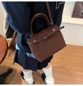 Detail of dark brown matte suede tote bag with leather strap buckle and texture
