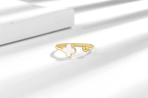 Detail of minimalist gold four-leaf clover open ring on artistic shadow background