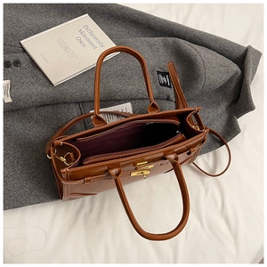 Detailansicht der braunen glänzenden Tasche mit goldenem Drehverschluss und PU-Leder