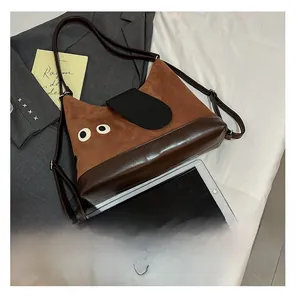 Dettaglio della borsa tote in pelle scamosciata con occhi cartoon e patchwork