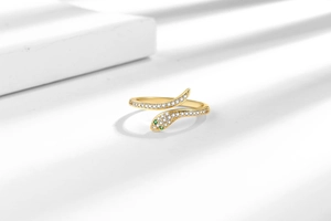 Macro detail of a gold-plated snake ring with white zircons and green gemstone eyes